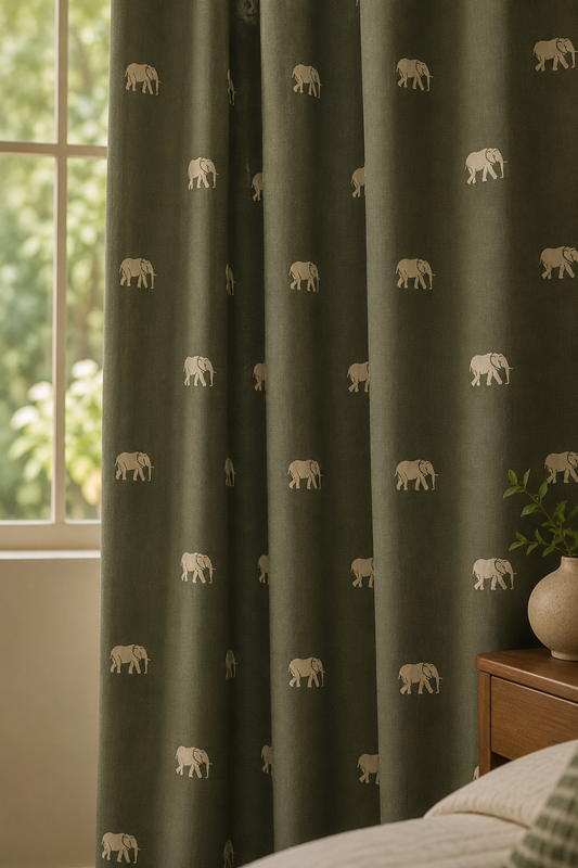 Dark olive green curtains with a repeating pattern of small beige elephants, hanging in front of a window in a bedroom setting.