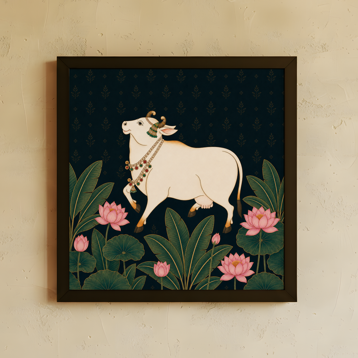 A framed art print featuring a cream-colored cow adorned with a decorative collar, walking among green lotus leaves and pink lotus flowers against a dark navy patterned background. The print is housed in a dark brown frame and mounted on a textured beige wall.