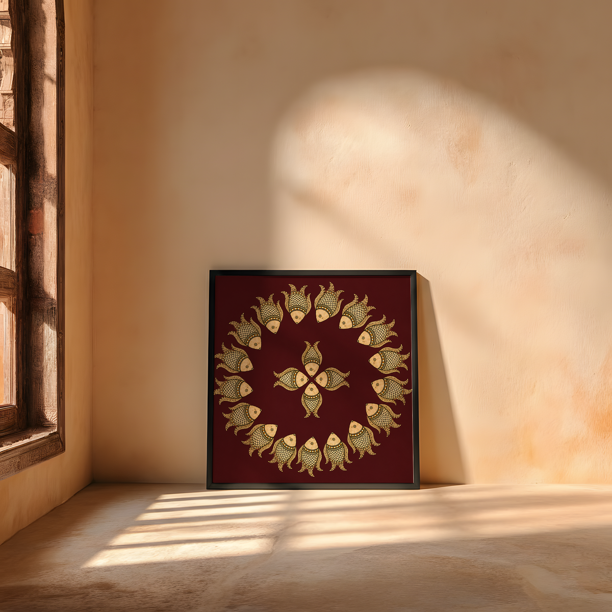 A square framed wall art print leaning against a sunlit plaster wall on the floor. The artwork features a deep maroon background with a circular arrangement of small gold fish around a central gold motif.