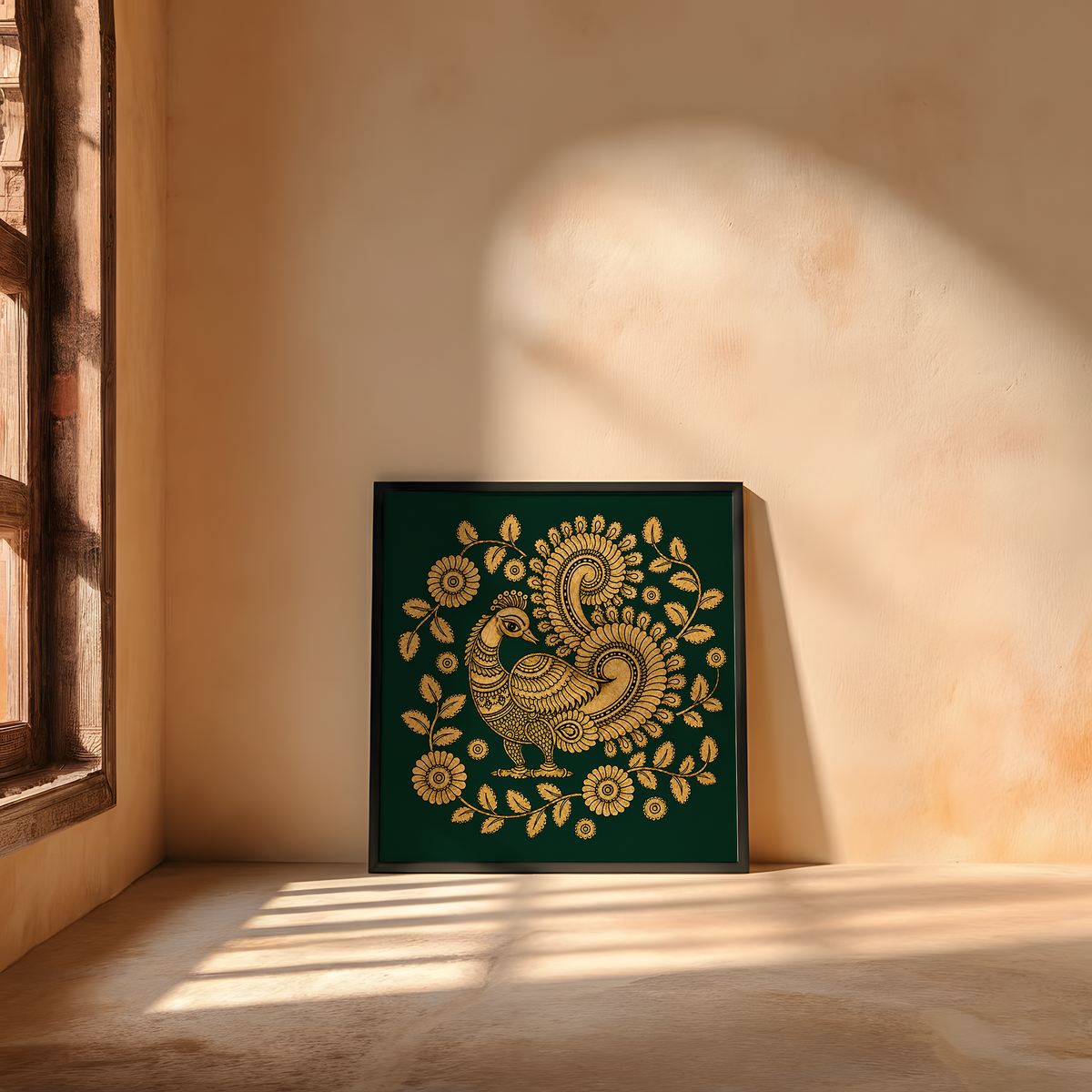 A square framed art print featuring a detailed gold paisley and floral design on a dark green background, leaning against a warm beige plaster wall in a sunlit room.