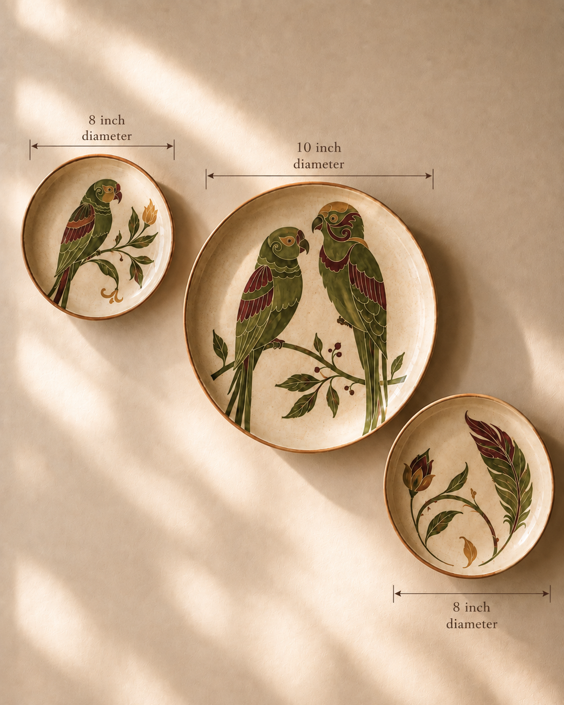Three decorative ceramic plates with parrot and botanical illustrations, shown with dimension arrows and text indicating 8 inch and 10 inch diameters against a warm beige background with soft window shadows.